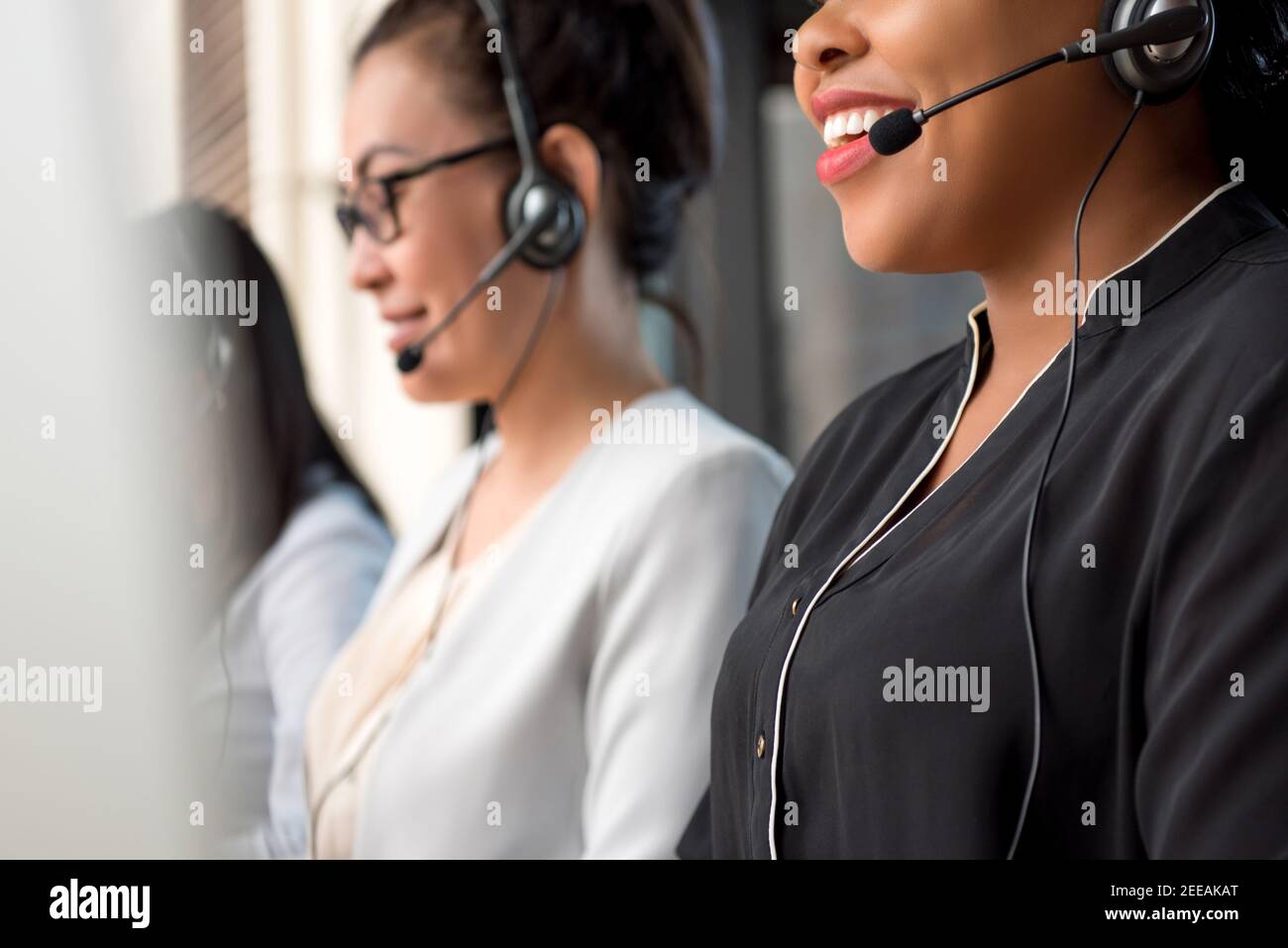 Team misto di donne che lavorano nel call center come telemarketing agenti del servizio clienti Foto Stock