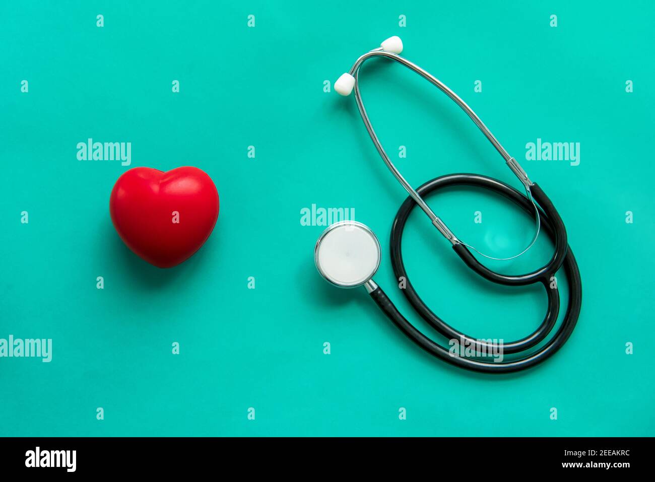 Sfera rossa a forma di cuore con stetoscopio su sfondo verde, assistenza sanitaria e concetto medico Foto Stock