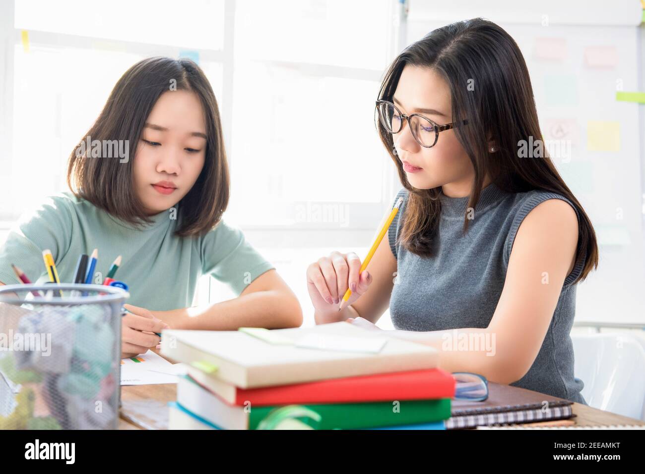 Gruppo di studentesse asiatiche del college cinese che fanno l'assegnazione a. il tavolo in classe Foto Stock