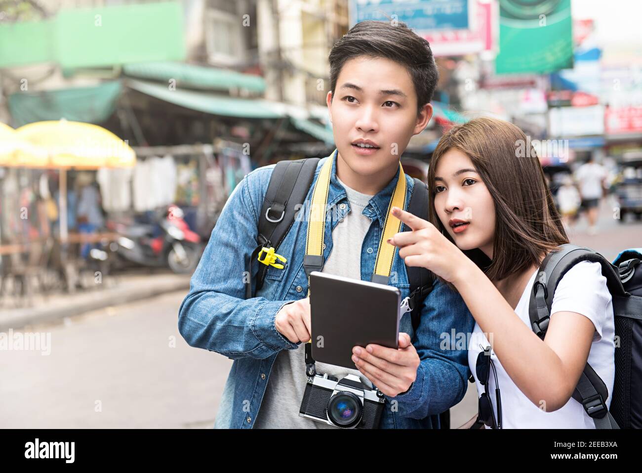 Coppie asiatiche turisti backpackers utilizzando tablet per trovare la posizione durante il viaggio in vacanza a Khao San Road, Bangkok, Thailandia Foto Stock
