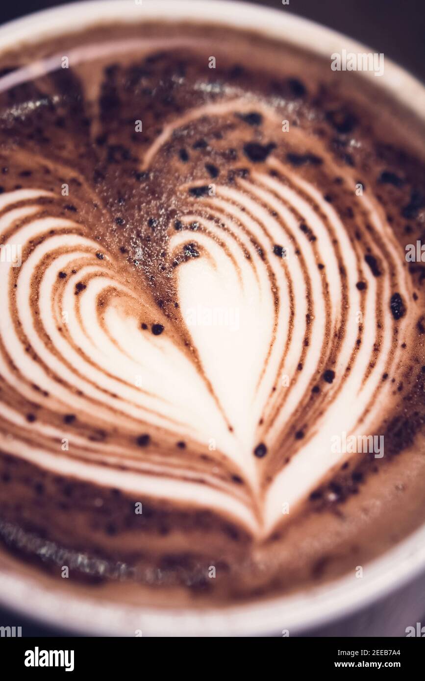 Primo piano della forma del cuore latte art sulla parte superiore di bevanda calda al cioccolato fondente nella tazza Foto Stock