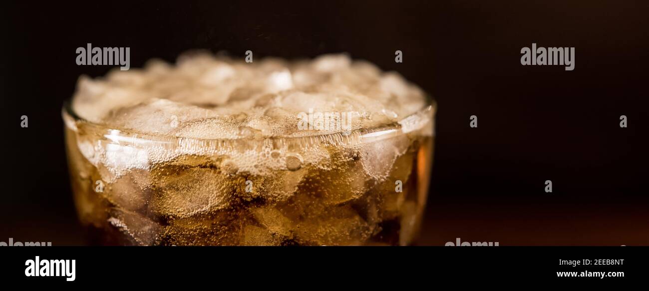Primo piano di bibita fredda di Sodar di cola nel bicchiere con bolla di schiuma sulla parte superiore, banner panoramico con spazio per la copia Foto Stock