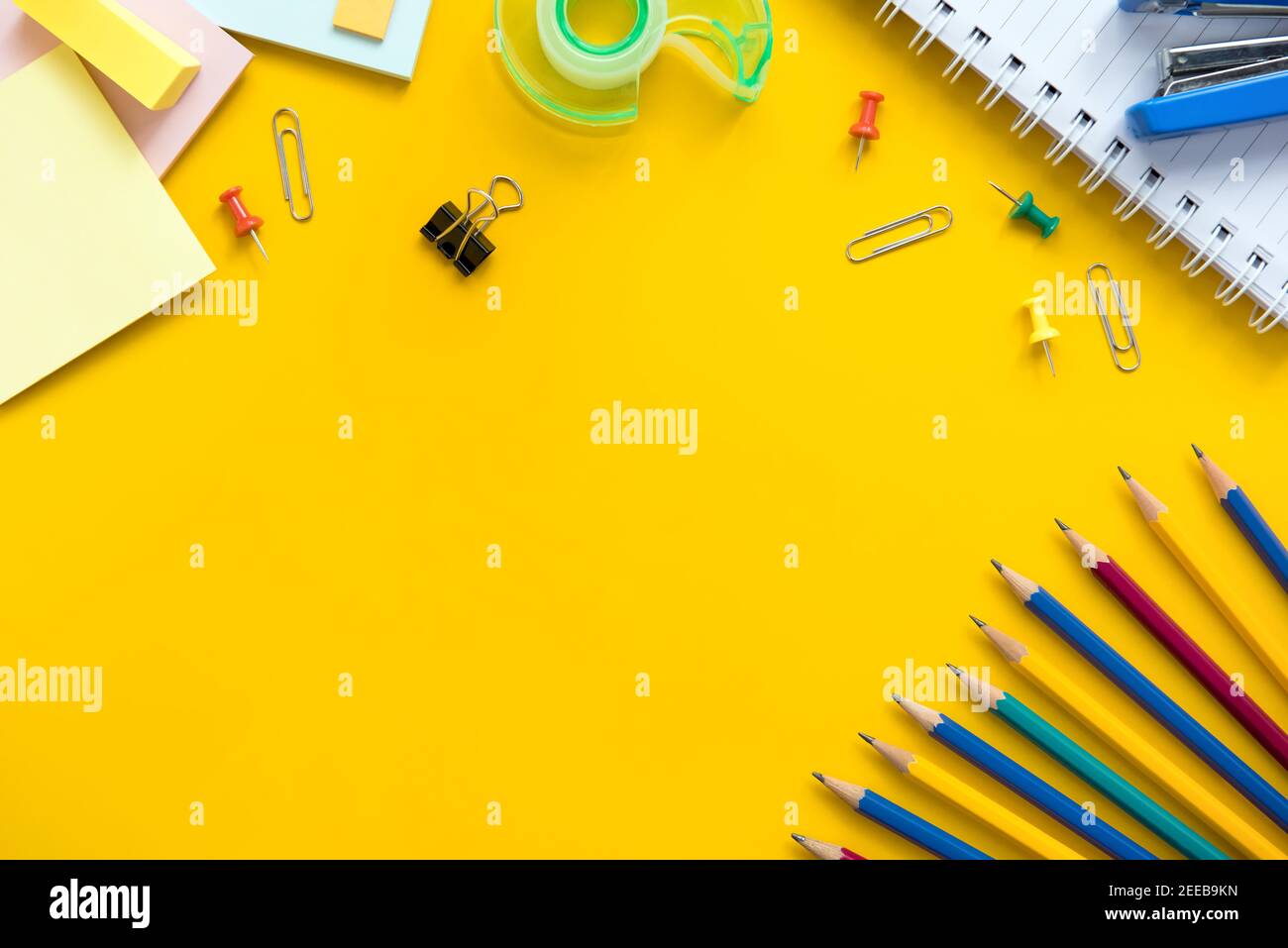 Forniture colorate per ufficio e materiale didattico su sfondo giallo con copia spazio Foto Stock