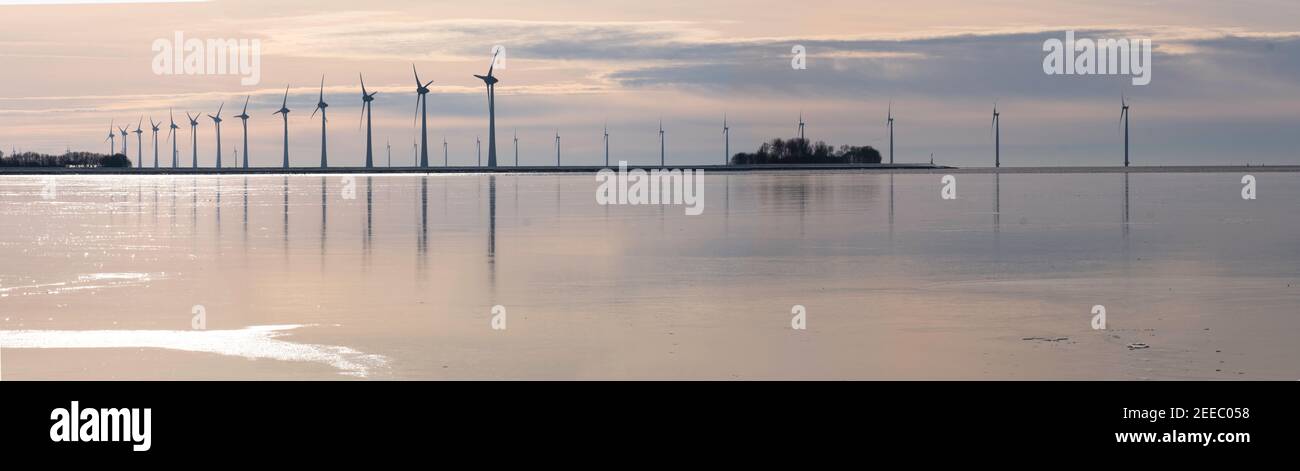 Parco dei mulini a vento nella baia di Lemmer nella Ijsselmeer, la più grande azienda eolica offshore dei Paesi Bassi. Scena invernale, mulini a vento sono riflessi in Foto Stock