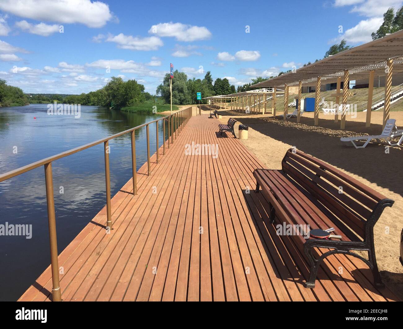 Ponte di legno e panca con passeggiata a riva del fiume banchina. Passerella all'aperto sulla riva del fiume Foto Stock