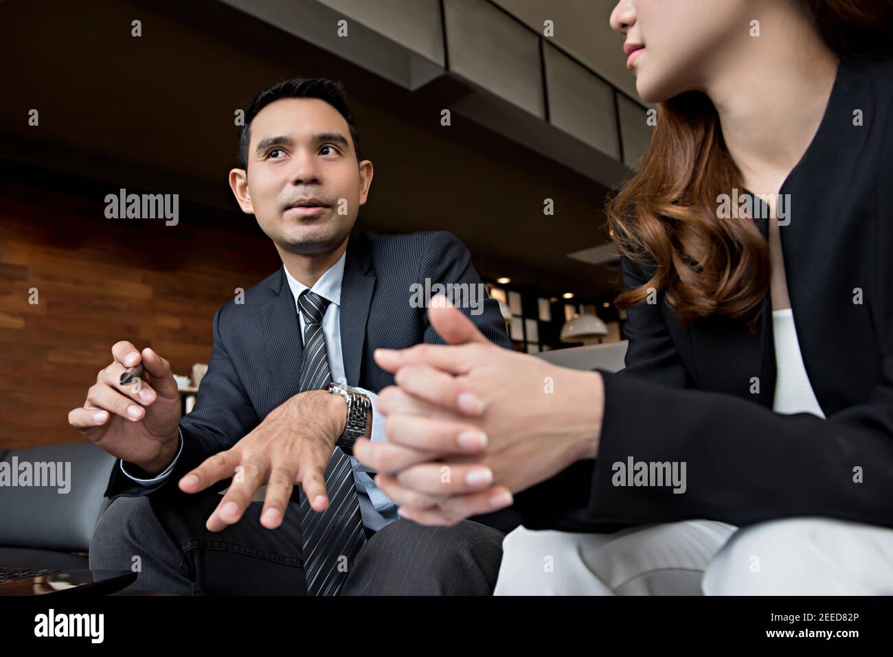 Uomo d'affari asiatico e donna d'affari che discute un programma di riunione in un caffetteria lounge Foto Stock