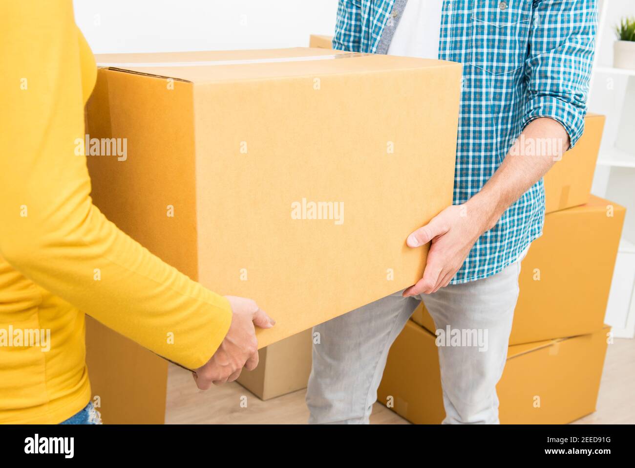 Coppia aiutandosi a vicenda portando una scatola, muovendosi nella loro nuova casa. Foto Stock