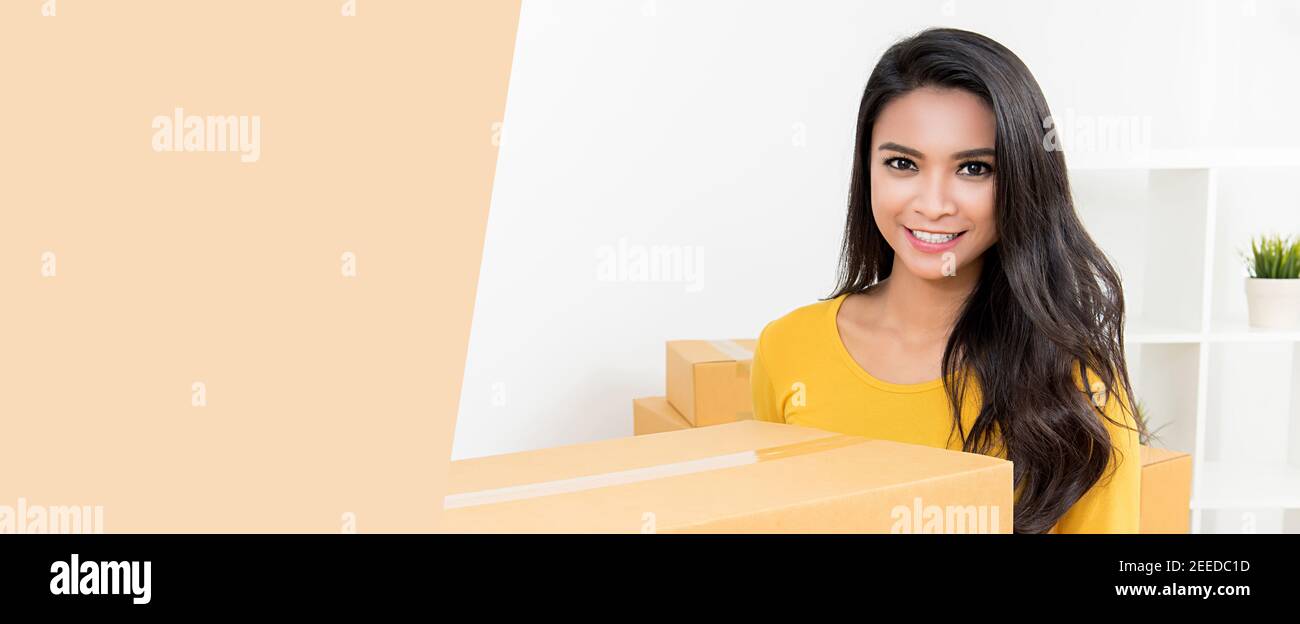 Bella donna asiatica che trasporta una scatola che si muove nel suo nuovo home - banner web orizzontale con spazio per la copia su sinistra Foto Stock