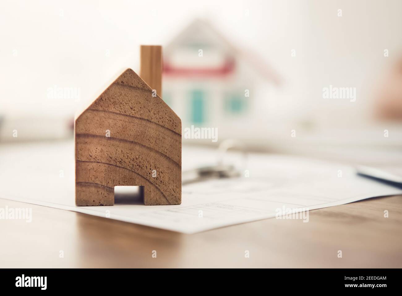 Modello di piccola casa di legno con documento di carta d'accordo sul tabella - concetto di bene immobile e di affari di proprietà Foto Stock