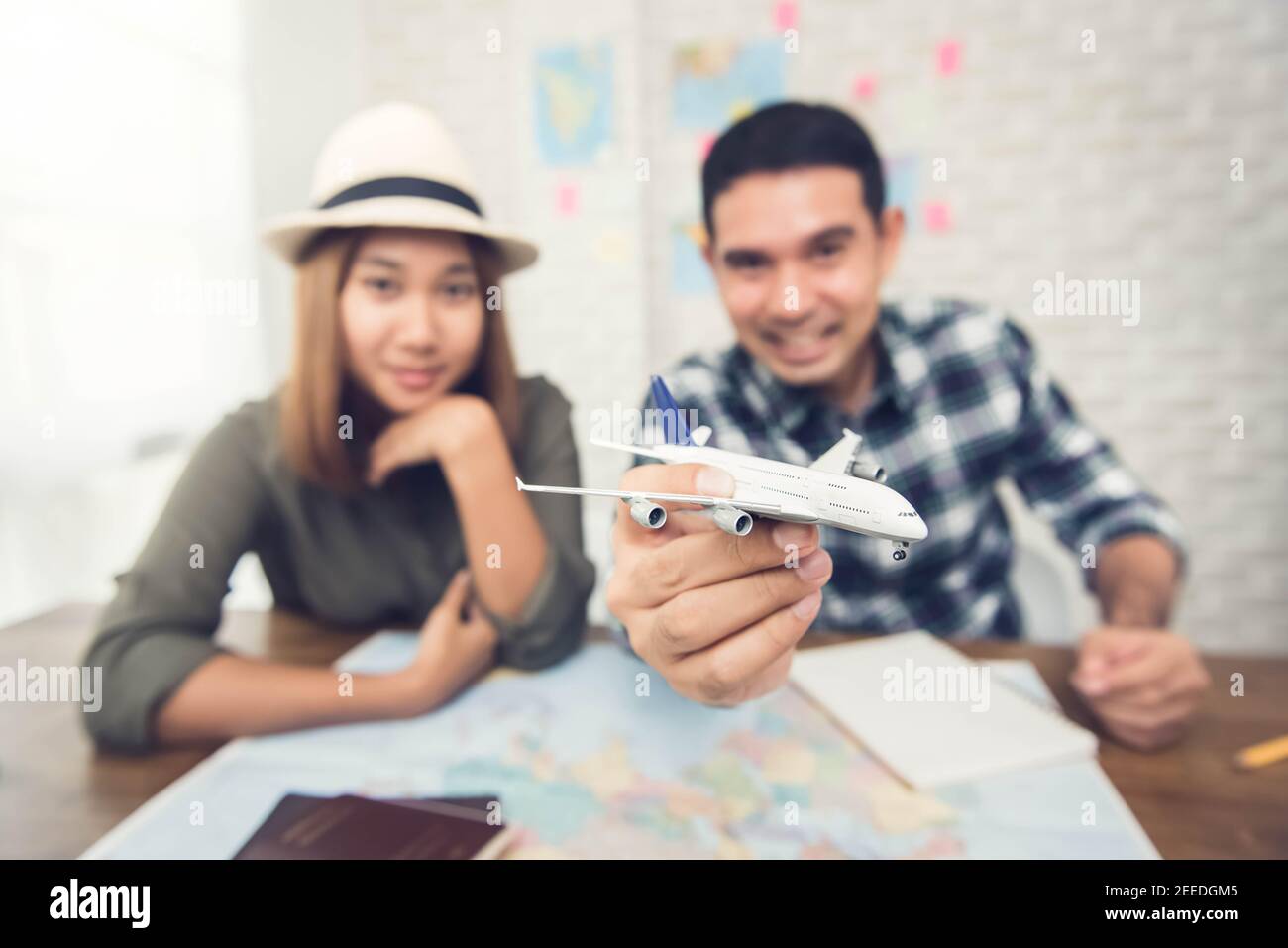 Coppia asiatica che piangono il loro viaggio di vacanza usando la mappa e giocando con un aereo giocattolo modello, ottenendo eccitato circa il loro viaggio Foto Stock