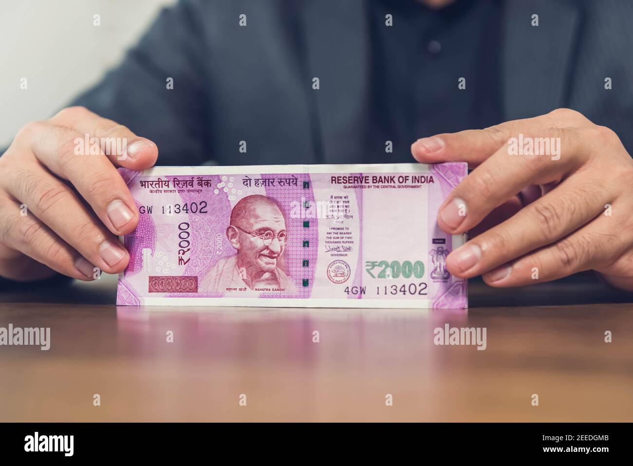 Un uomo d'affari in un istituto finanziario che conta e mostra denaro, le banconote in rupia indiana al tavolo Foto Stock
