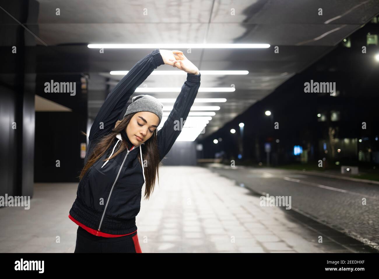Donna che allunga entrambe le mani prima del suo allenamento all'aperto Foto Stock