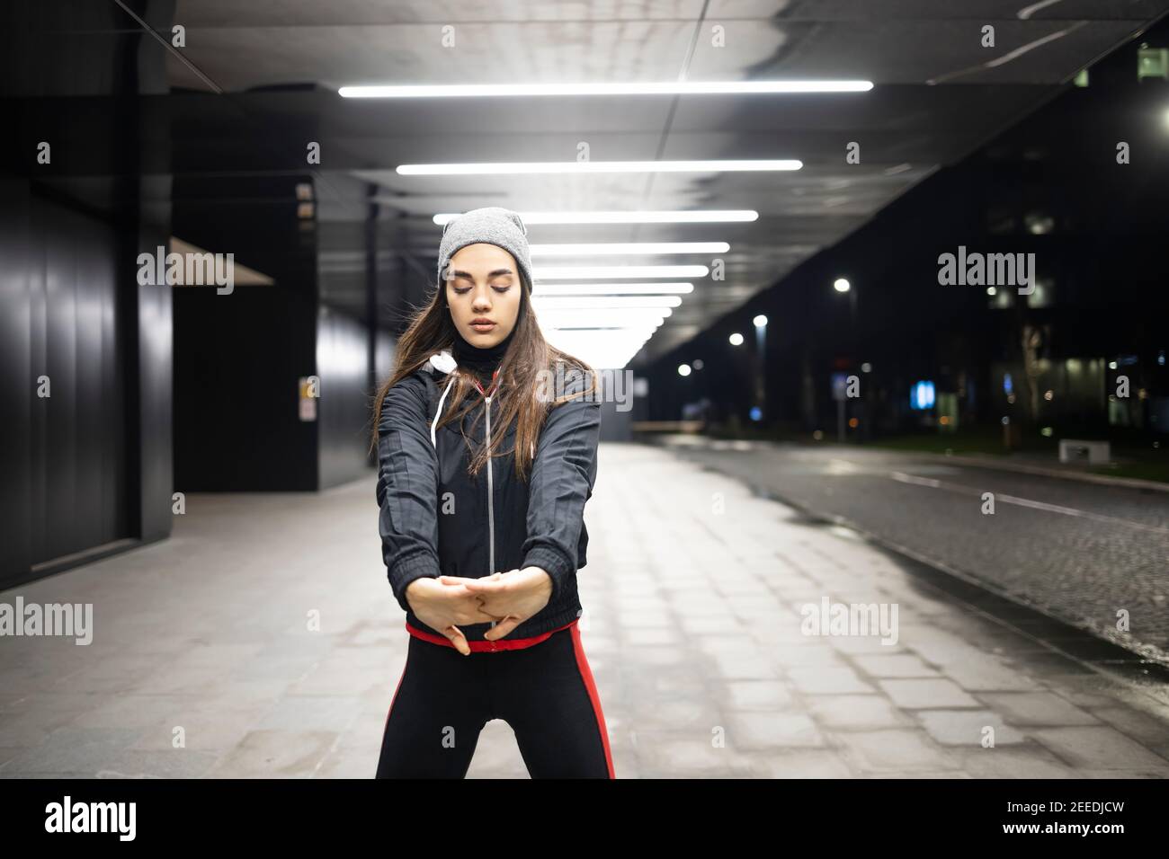 Donna che allunga entrambe le mani prima del suo allenamento all'aperto Foto Stock