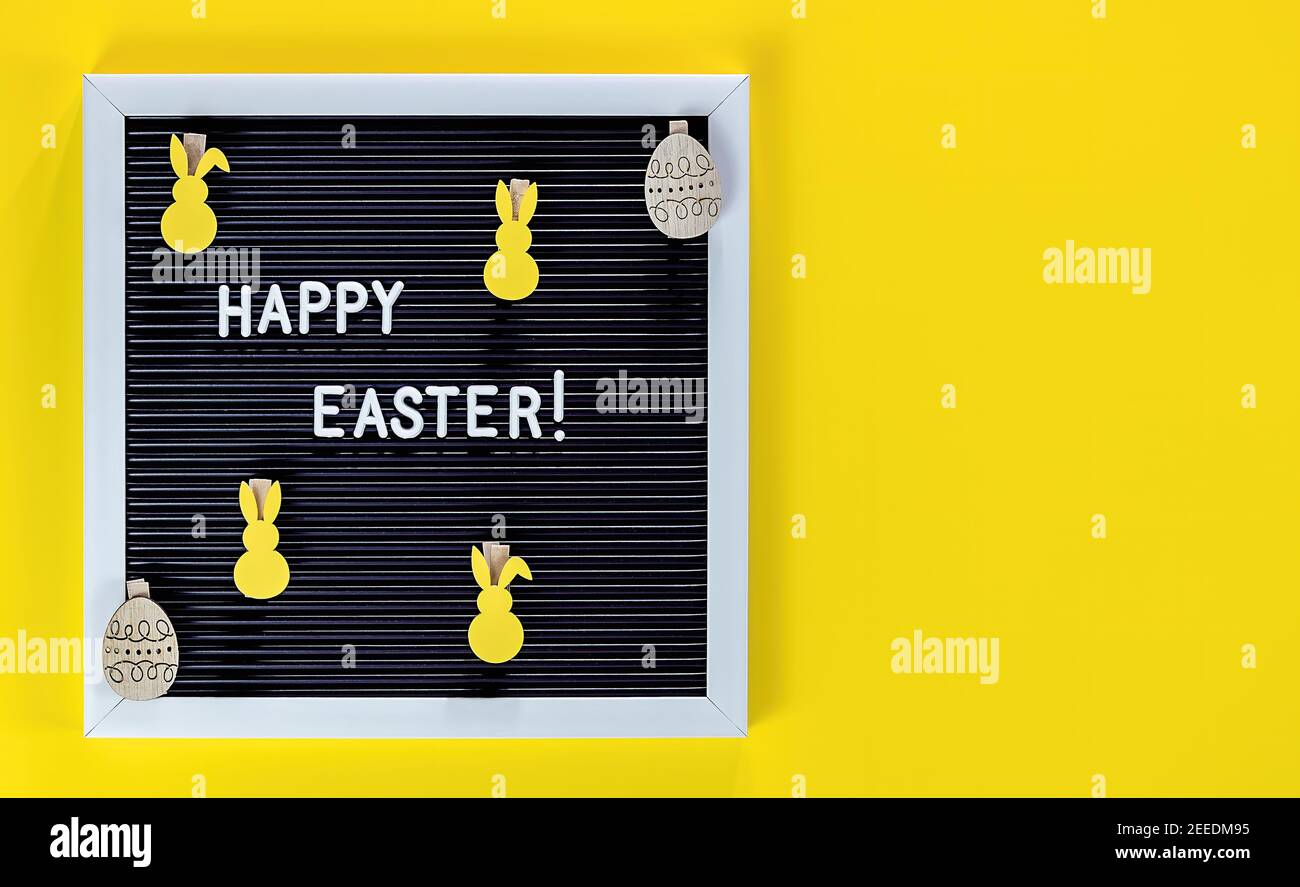 Coniglietto di Pasqua e bordo di lettera su sfondo giallo. Piatto di concetto di celebrazione pasquale. Foto Stock