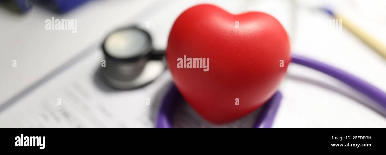 Stetoscopio e cuore rosso sul tavolo dell'ufficio medico. Foto Stock