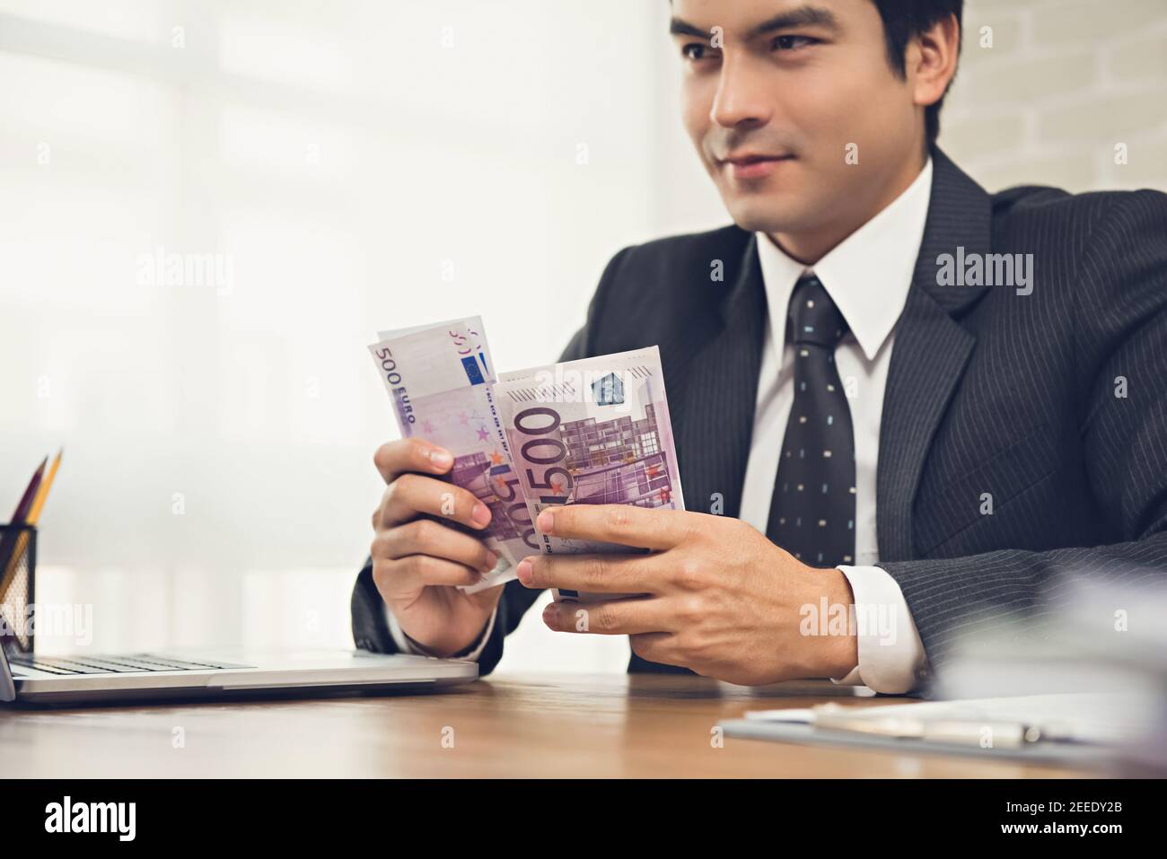 Uomo d'affari che conta denaro, banconote in euro, al suo banco di lavoro - concetti finanziari e d'investimento Foto Stock