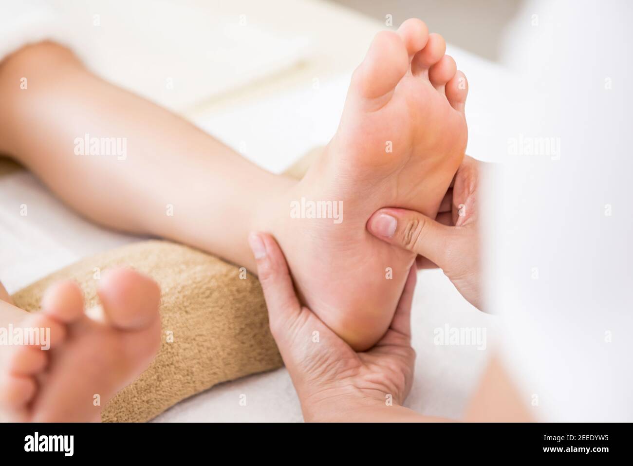 Terapista professionista che offre rilassante riflessologia massaggio tailandese del piede ad un donna in spa Foto Stock