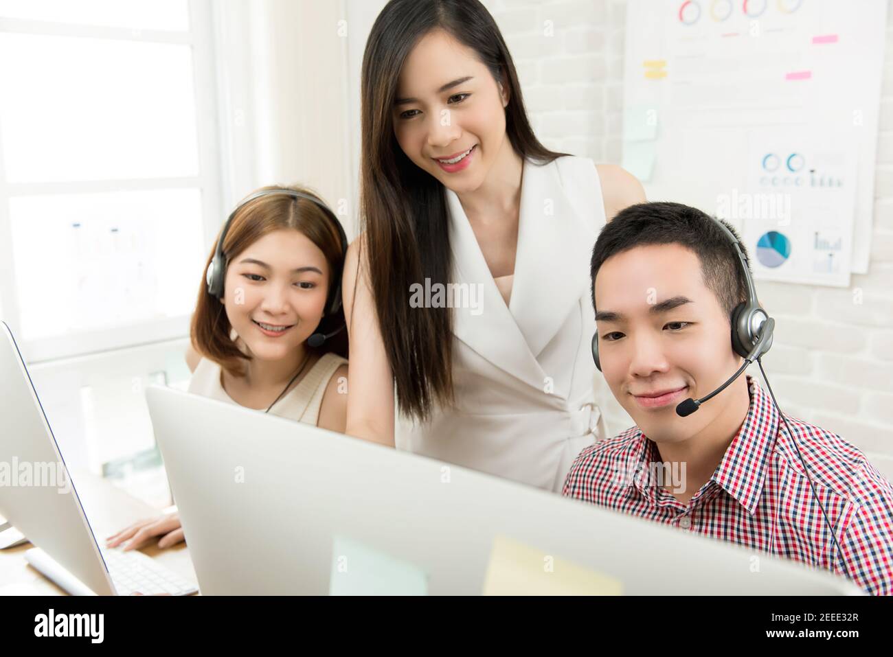 Una donna asiatica che parla di lavoro con l'agente del servizio di telemarketing team nel call center Foto Stock
