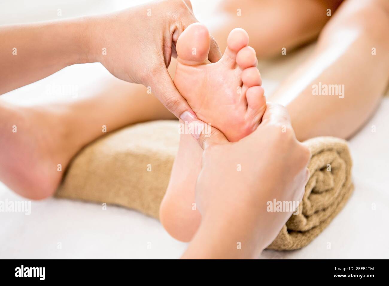 Terapista professionista che offre rilassante riflessologia massaggio tailandese del piede ad un donna in spa Foto Stock