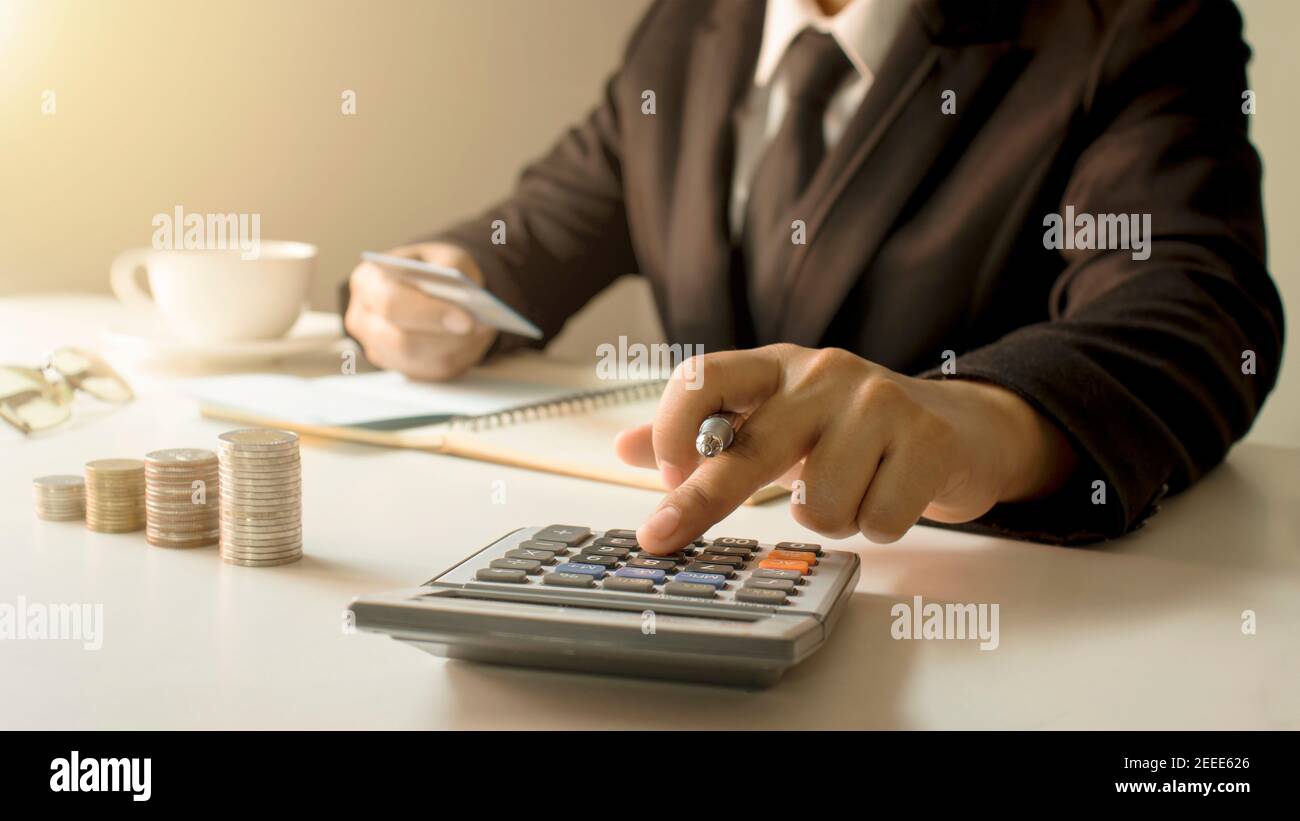 Gestione del conto e concetto di risparmio di denaro, un primo piano di una donna che utilizza una calcolatrice per produrre rapporti di lavoro contabile.fuoco morbido Foto Stock