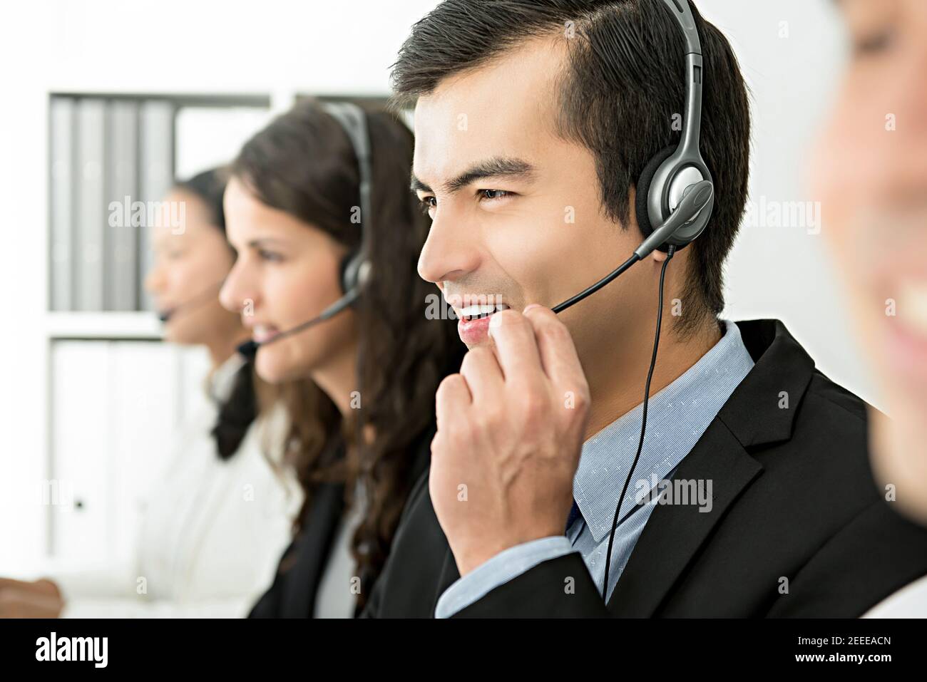 Sorridente allegro agente di servizio clienti di telemarketing maschile con il suo team, concetto di lavoro call center Foto Stock