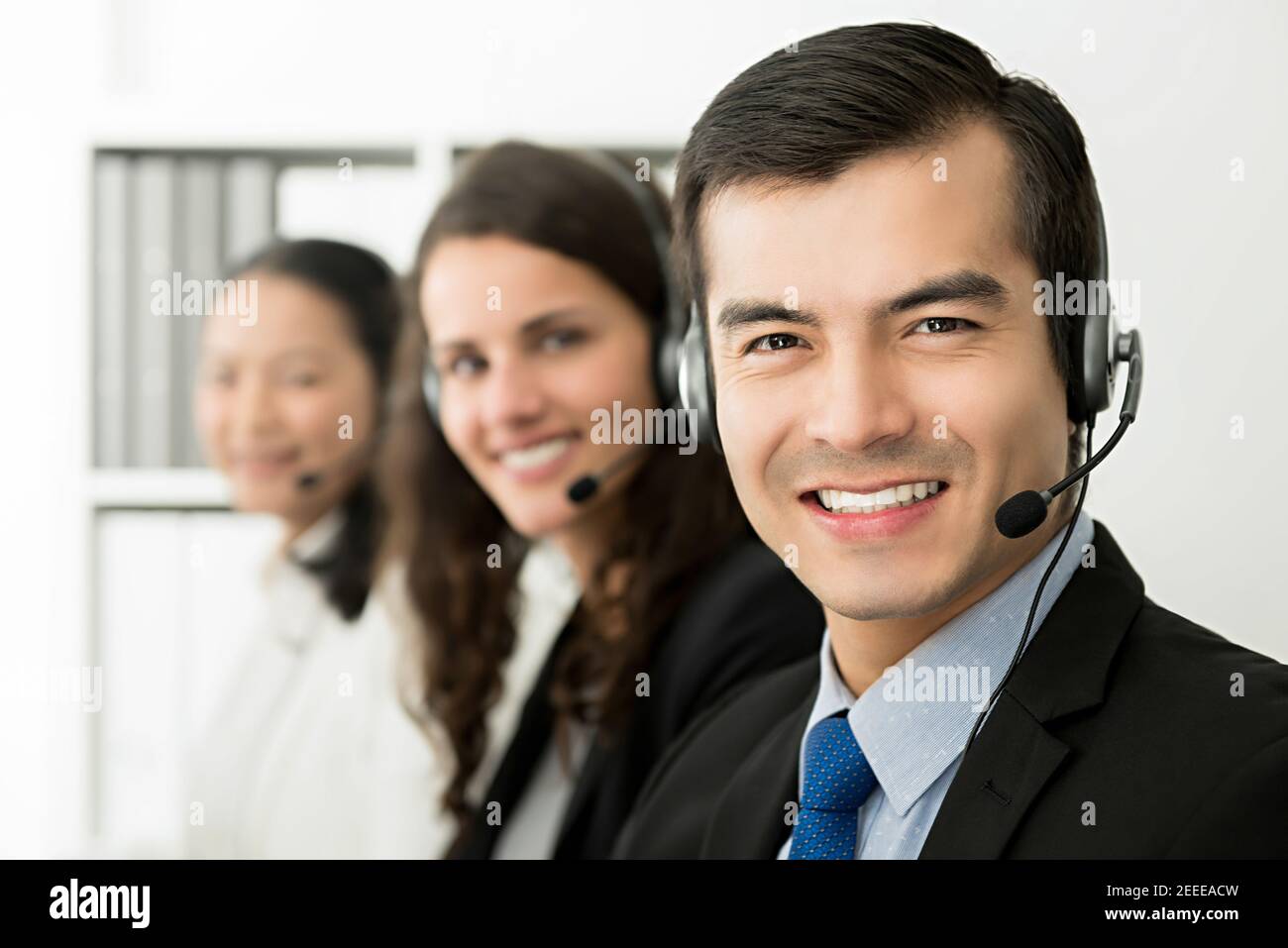 Sorridente allegro agente di servizio clienti di telemarketing maschile con il suo team, concetto di lavoro call center Foto Stock