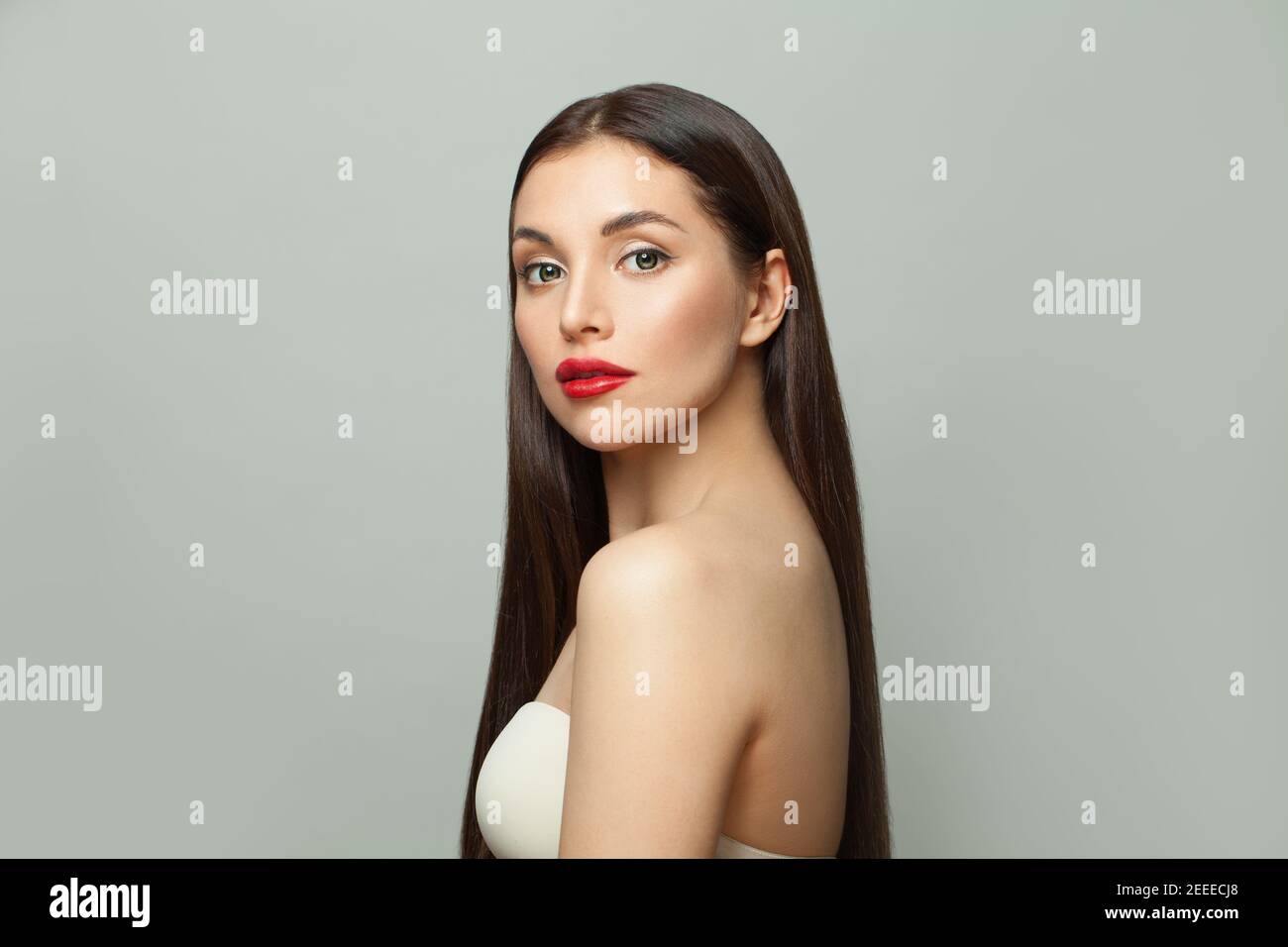 Perfetta brunetta giovane donna con pelle chiara e lunga brillantezza capelli lisci su sfondo bianco Foto Stock