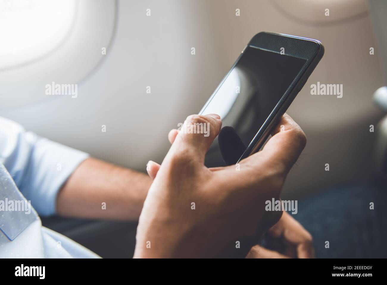 Il passeggero maschile ha appena spento il telefono cellulare sull'aereo durante il viaggio per un volo sicuro Foto Stock
