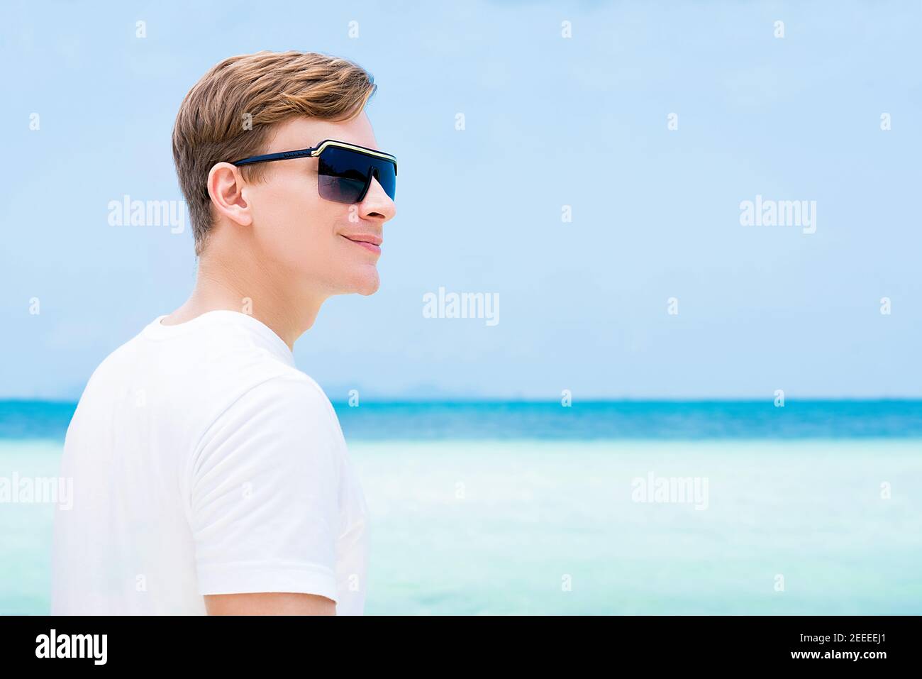 Uomo turistico sorridente e informale che indossa occhiali da sole sulla spiaggia vacanze estive Foto Stock