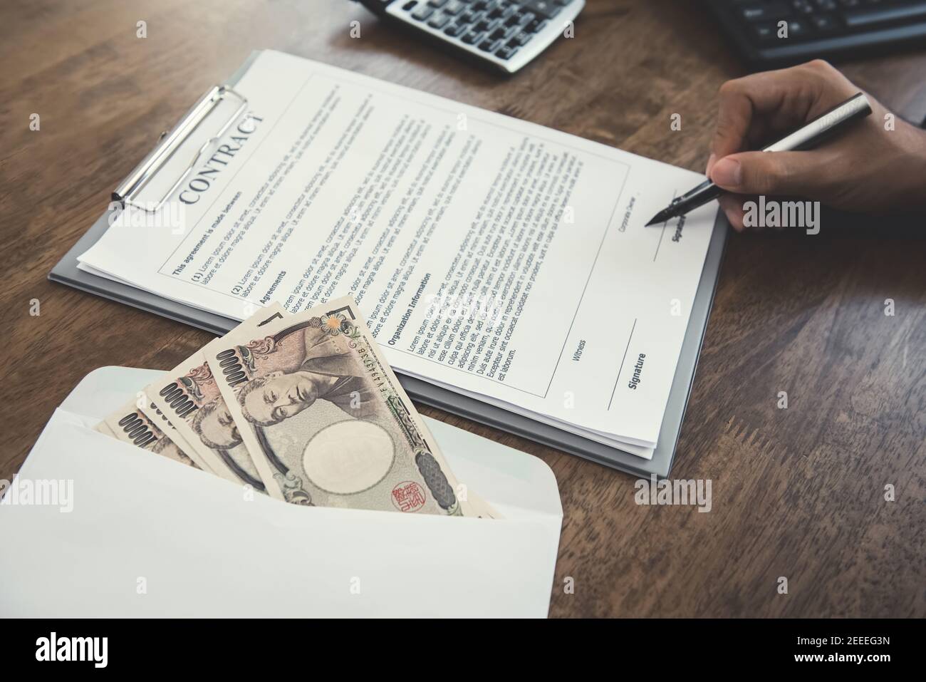 Mano che tiene il contratto di firma della penna con il denaro, le banconote di yen giapponesi, sul tavolo Foto Stock