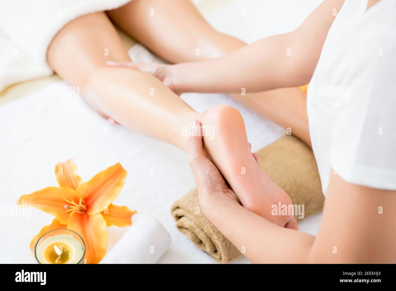 Terapista professionista che offre un rilassante massaggio tailandese con le gambe a olio una donna in spa Foto Stock