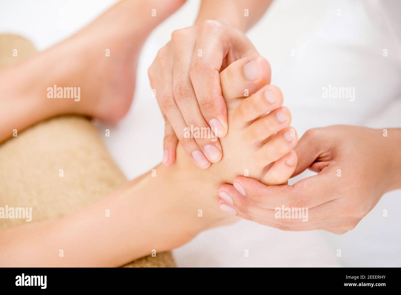 Terapista professionista che offre un rilassante massaggio tradizionale tailandese riflessologia plantare una donna in spa Foto Stock