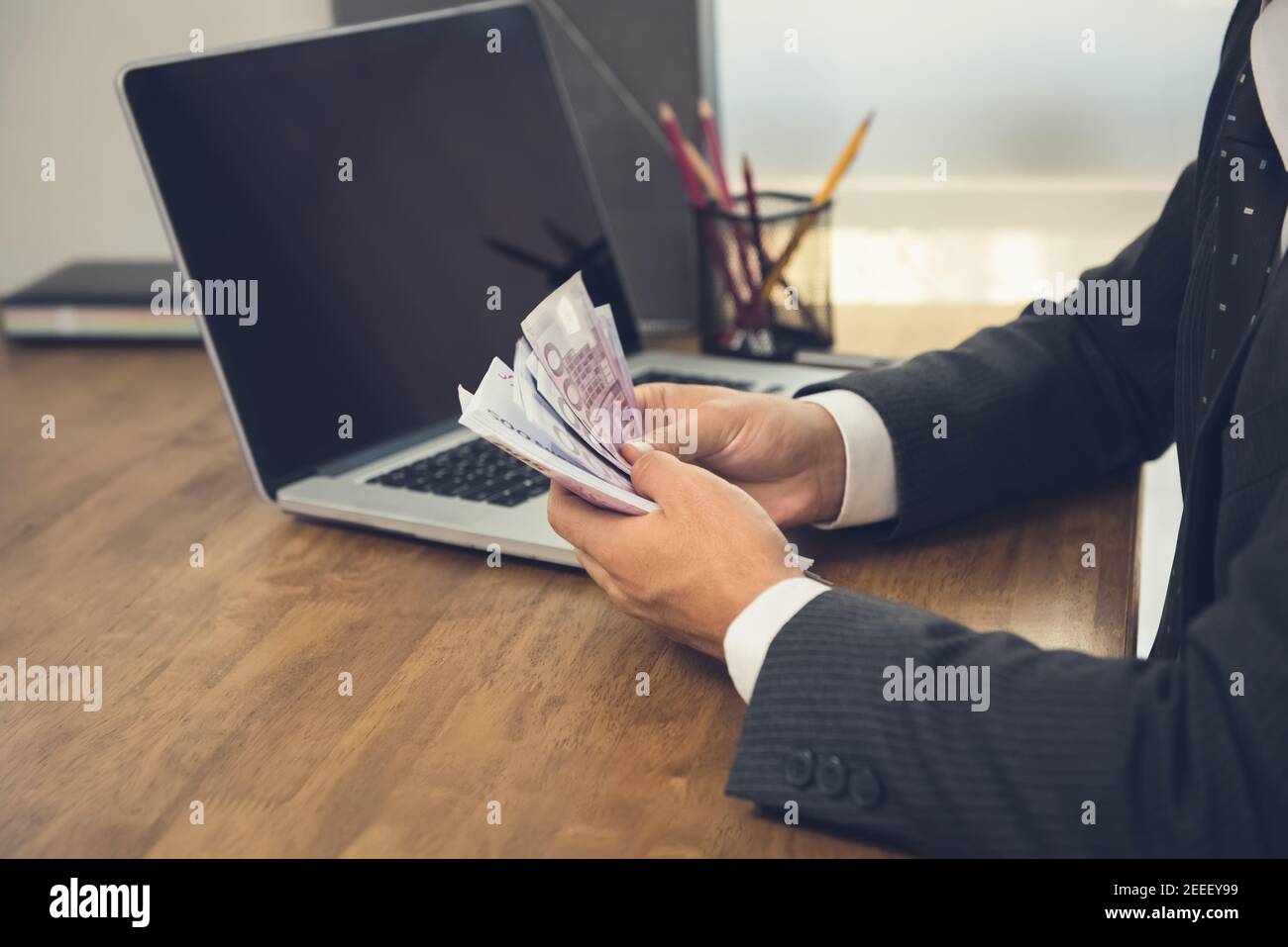 Uomo d'affari che conta denaro, banconote in euro, alla sua scrivania Foto Stock