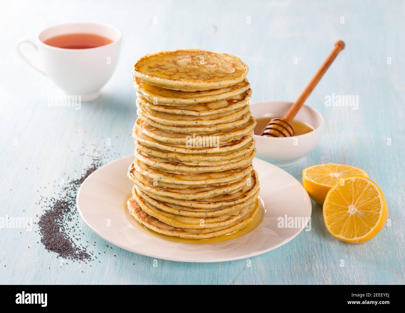 Frittelle al limone con semi di papavero e miele su sfondo blu. Deliziosi piatti fatti in casa Foto Stock