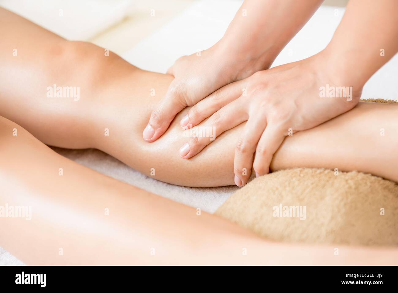 Terapista professionista che massaggia le gambe a una donna Foto Stock