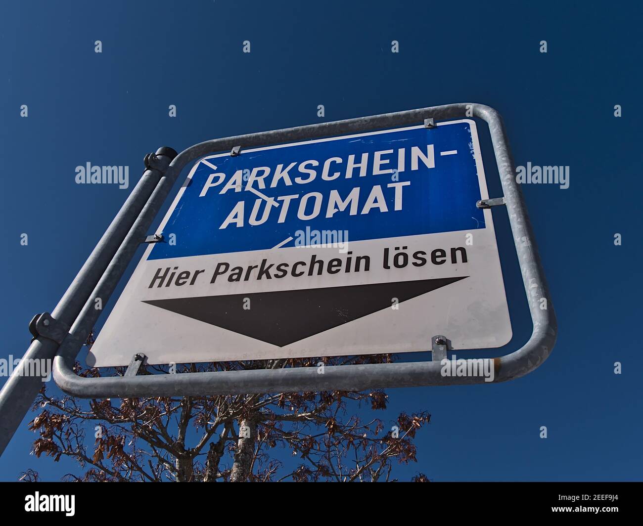 Vista ad angolo basso del cartello blu e bianco con freccia nera che conduce alla biglietteria di un parcheggio pubblico nel centro della città. Foto Stock