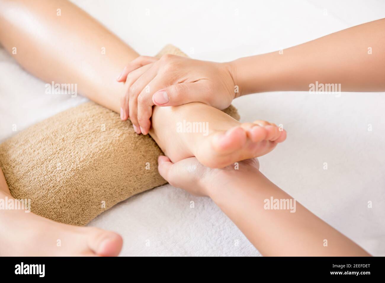 Terapista che offre massaggio tradizionale tailandese del piede ad una donna dentro centro benessere Foto Stock