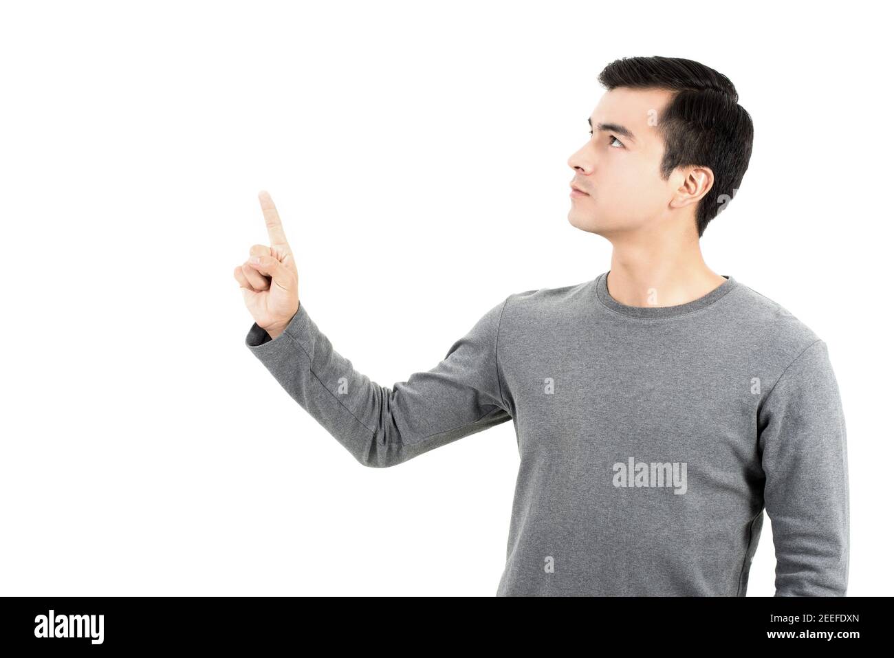 Giovane ispanico che punta il dito sullo spazio vuoto - studio girato su sfondo bianco Foto Stock