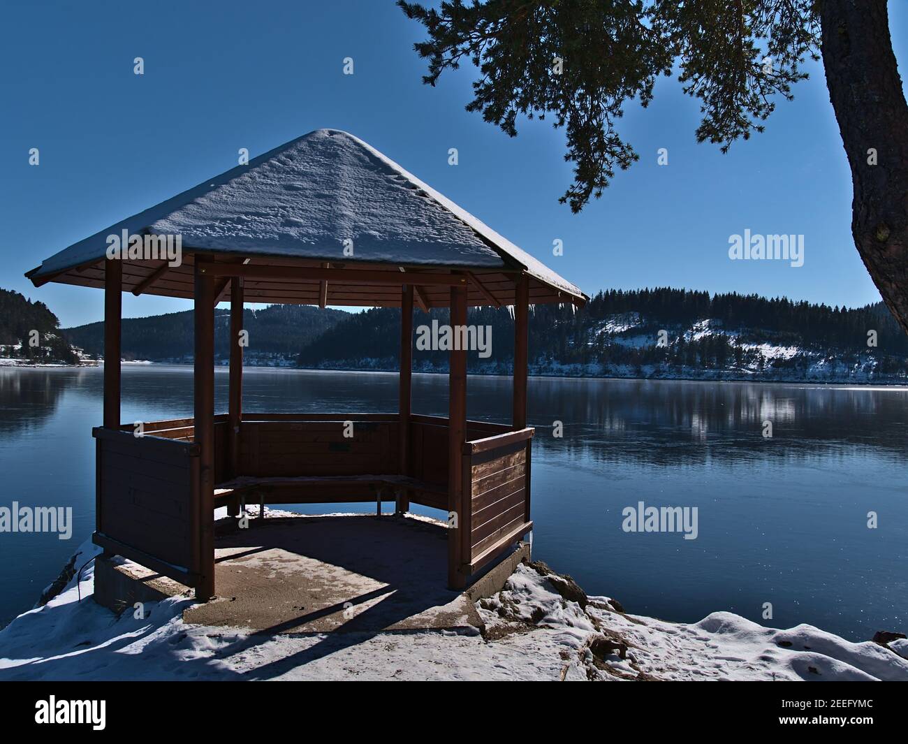 pavillon in legno innevato sulla riva del lago di Frozen Schluchsee, una meta turistica popolare nella catena montuosa della Foresta Nera, in Germania, in inverno. Foto Stock