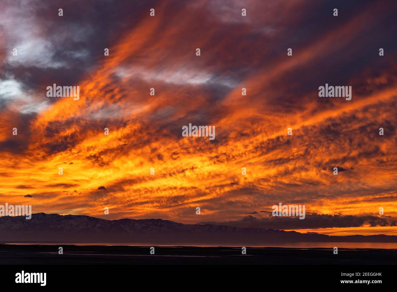 La luce ardente del sole che tramonta si riflette sul Great Salt Lake mentre si tramonta sulle Stansbury Mountains nella Tooele County, Utah, USA. Foto Stock