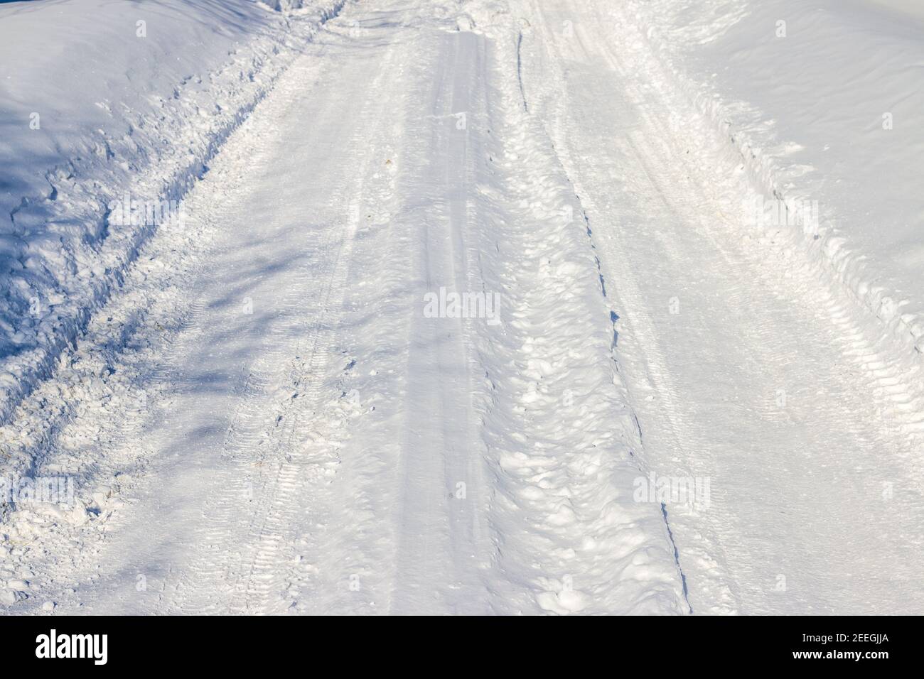 Neve coperta invernale strada. Fresca strada di neve. Strada coperta innevata. Fiocco di neve e ghiaccio alla luce del sole Foto Stock