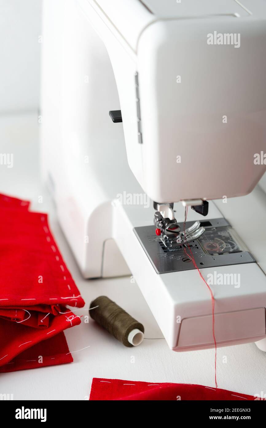 Moderna macchina da cucire con tessuto rosso, taglio e cucito a casa, per il tempo libero a casa e hobby Foto Stock