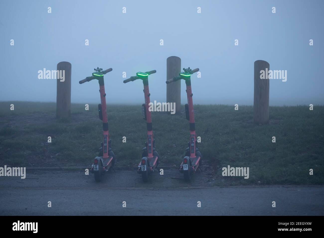 3 e-Scooters parcheggiati al limitare di Abington Park in Park Avenue South, Northampton, Inghilterra, Regno Unito. Foto Stock