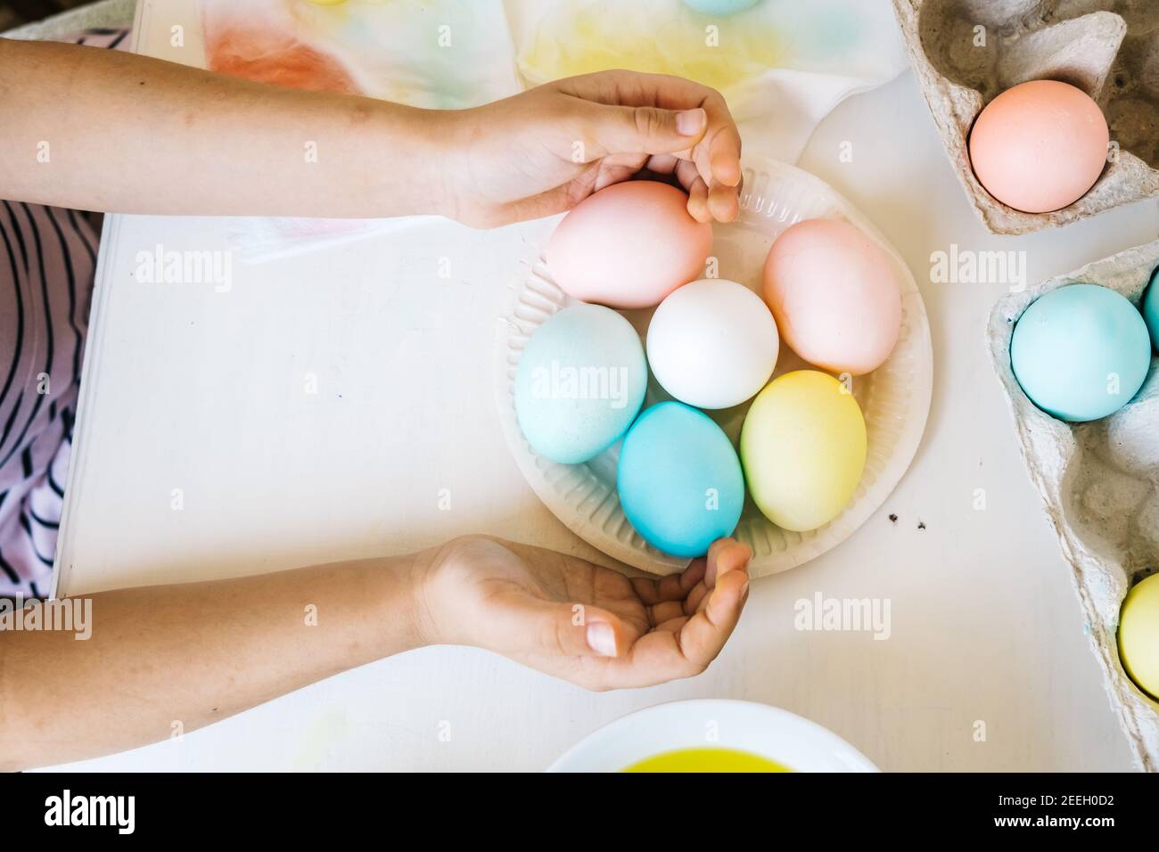 Primo piano su colorate uova di pasqua tinte in mani di bambino. Preparandosi a celebrare Pasqua. Vista dall'alto, colori pastello Foto Stock