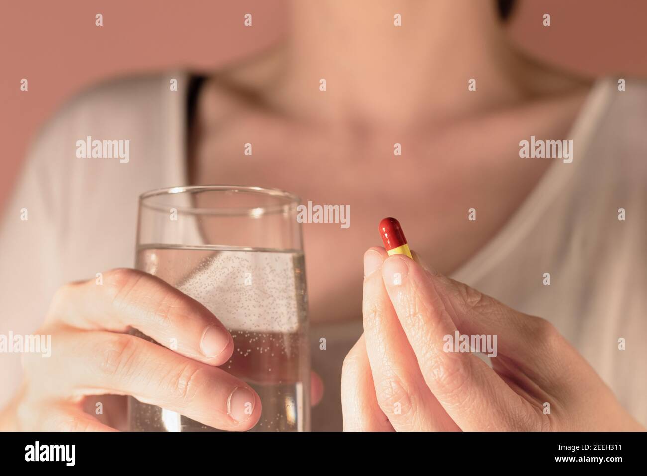 Primo piano di una donna che detiene una pillola di medicinale e un bicchiere d'acqua Foto Stock