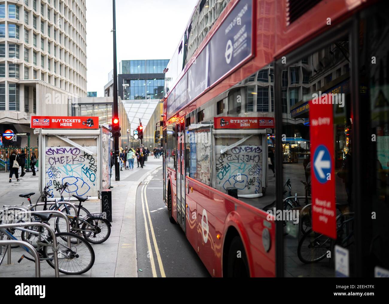 Scena stradale nel centro città con l'iconico maestro di rotta londinese Autobus rosso in attesa di passeggeri sulla trafficata Regent Street con vandalismo graffiti su edifici Foto Stock