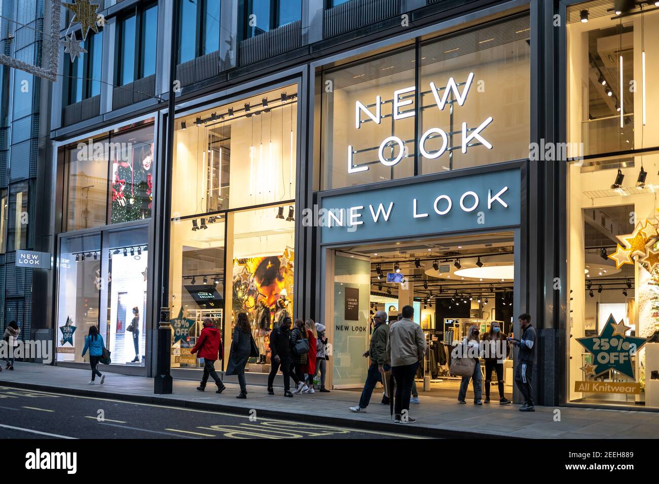 Abbigliamento nuovo look moderno centro città negozio con marchio logo e segno illuminato di notte occupato con i turisti e. acquirenti Foto Stock