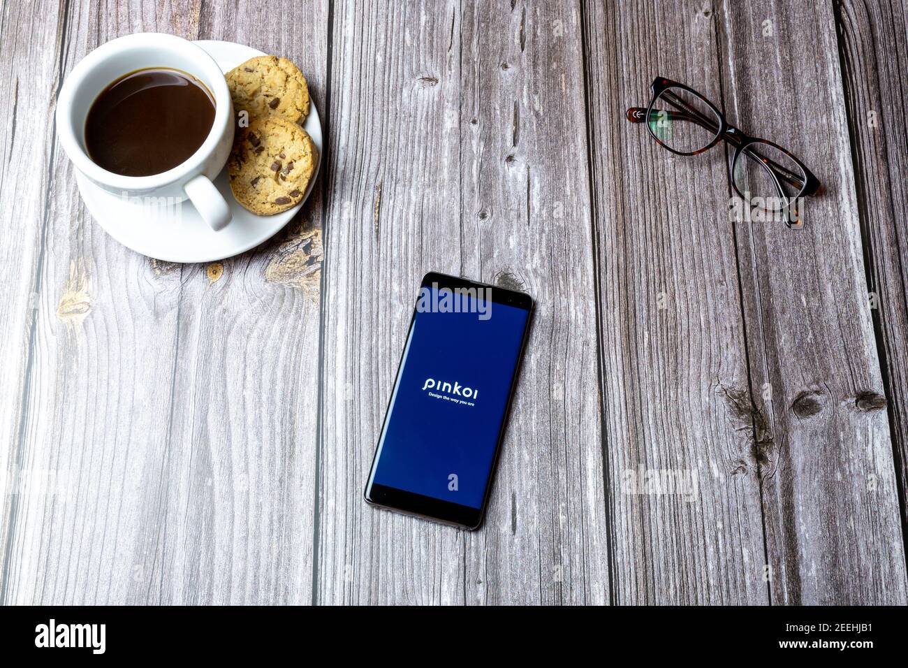 Un telefono cellulare o un telefono cellulare posato su un legno Tavolo con l'app Pinkoi aperta sullo schermo Foto Stock
