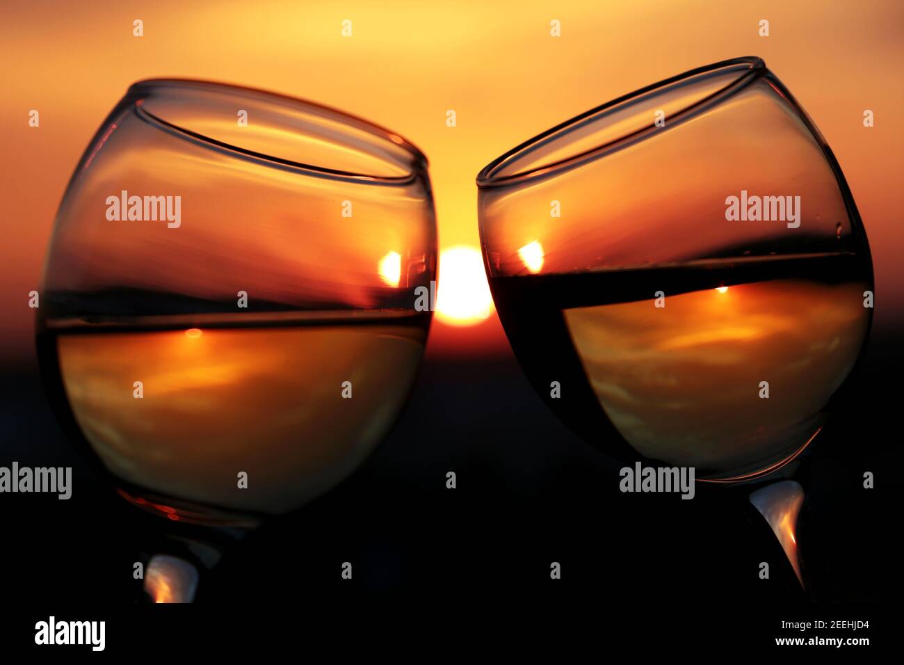 Silhouette di due bicchieri con vino bianco su sfondo tramonto, fuoco selettivo. Coppia clink bicchieri, concetto di celebrazione, serata romantica, amore Foto Stock