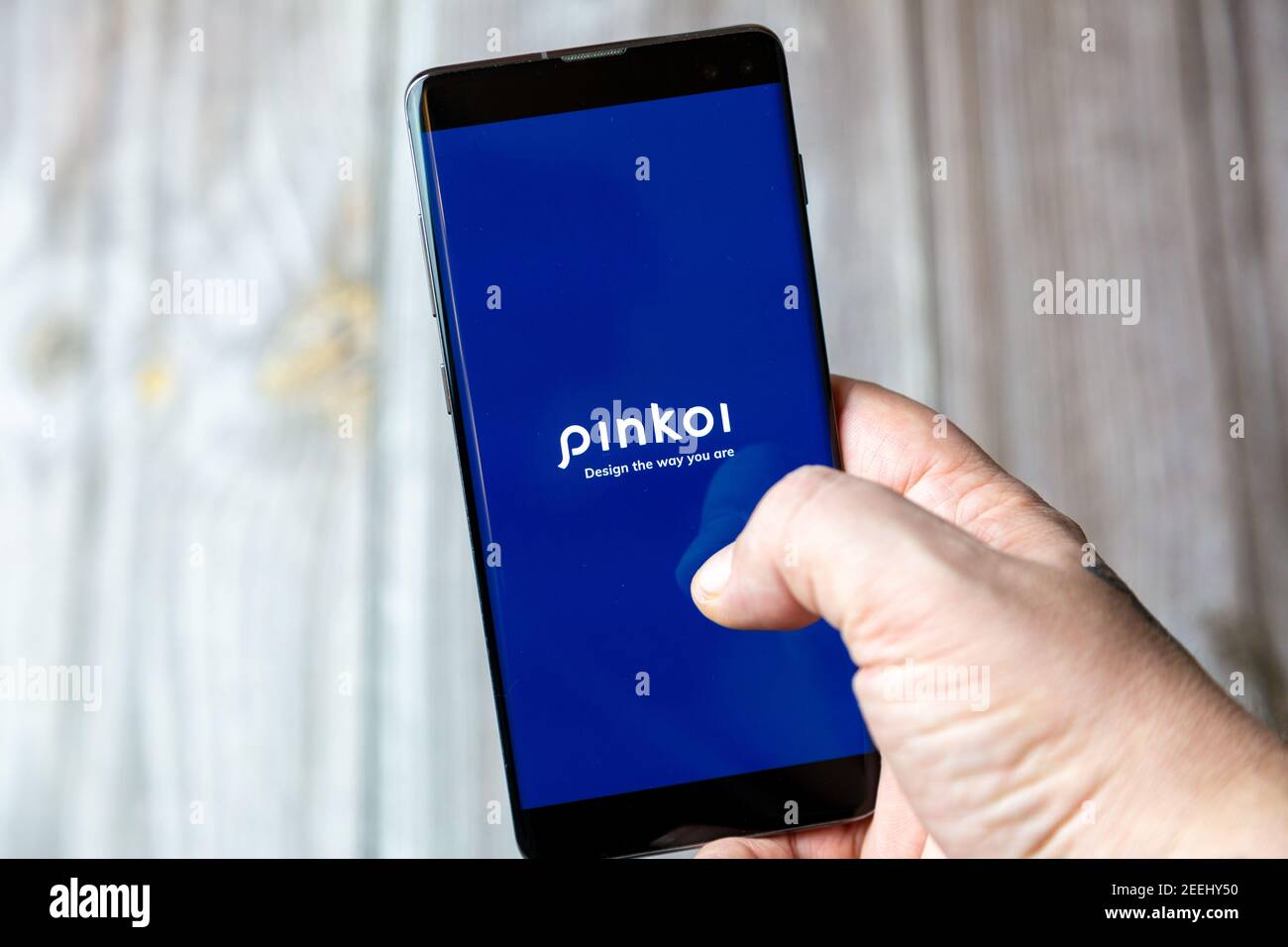 Un telefono cellulare o un telefono cellulare in attesa in un Mano con l'app Pinkoi aperta sullo schermo Foto Stock